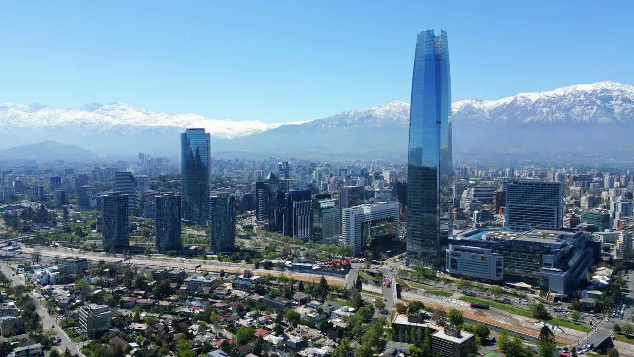 Santiago, Chile drone aerial pan over Costanera Center and skyline with snow-capped Andes in clear midday light