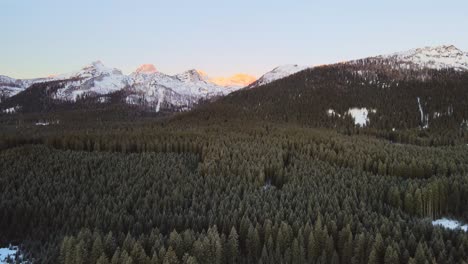 nature captured with a drone with landscape and mountains covered in snow at golden hour at sunrise with beautiful forest and surrounding hills captured in slovenia above forest pokljuka in 4k