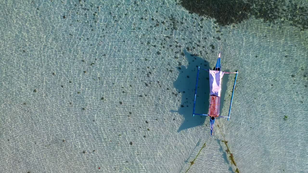 Aerial of Philippine Bangka boat anchored at bay. Turquoise tropical sea water