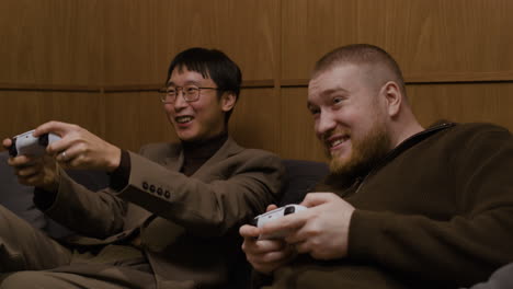 dos hombres jugando videojuegos en un sofá