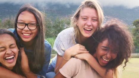 four happy teenage girls piggybacking outdoors, close up