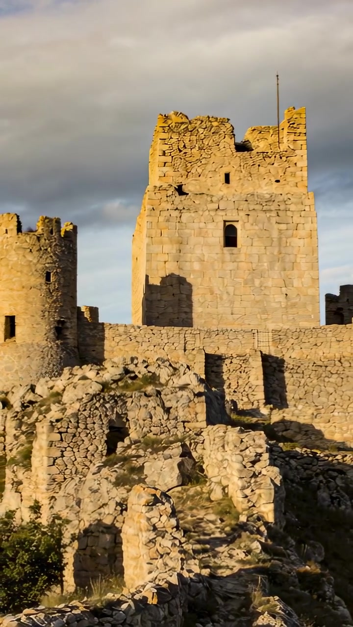 Video verticale: Rivelando un mastio in pietra, la telecamera si inclina dalle rovine inferiori in cima alla collina per mostrare l'intera altezza.