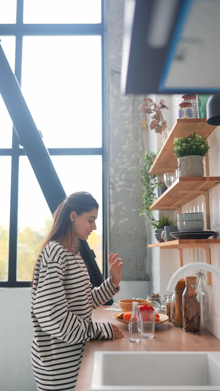 mujer alcanzando el vidrio en el estante de la cocina