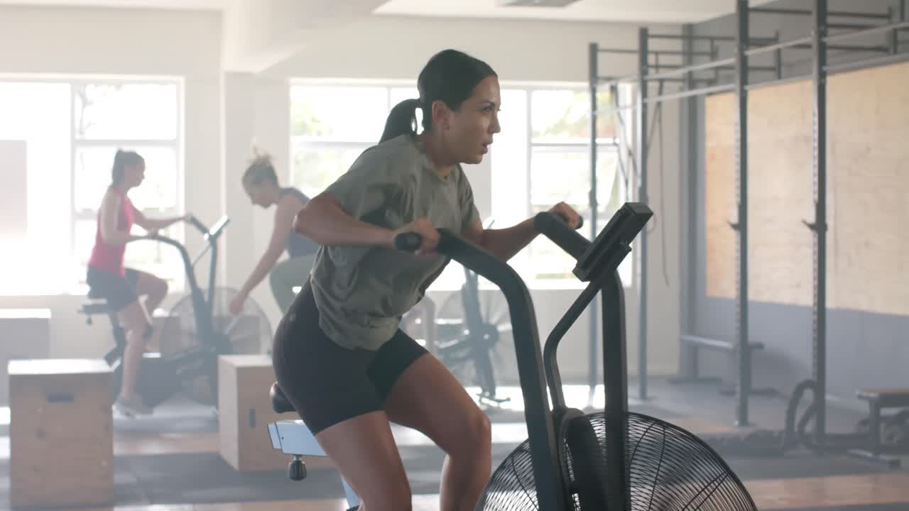 mujer caucásica determinada entrenando en bicicleta elíptica en el gimnasio, en cámara lenta