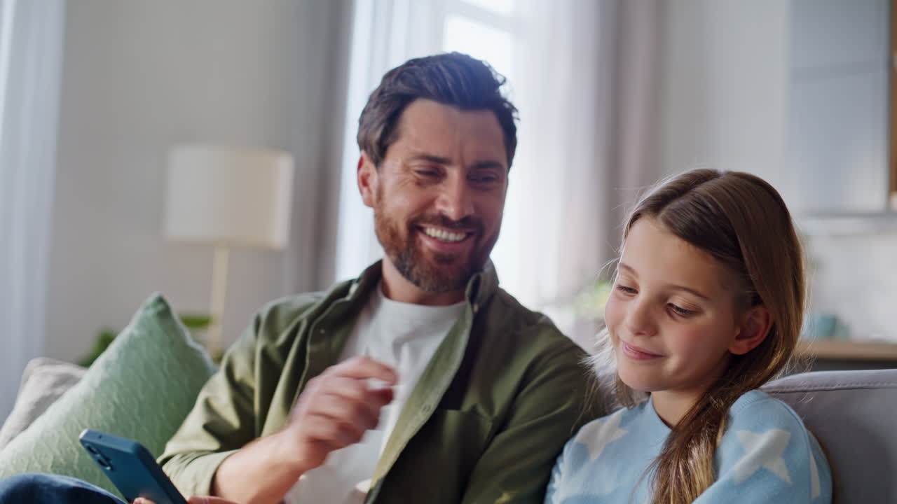 Primo piano di una famiglia spensierata che guarda i telefoni e si gode il tempo libero digitale a casa nel fine settimana