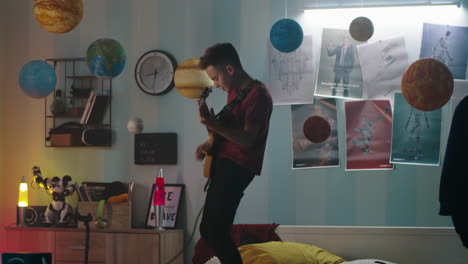 teenager playing guitar in a decorated bedroom