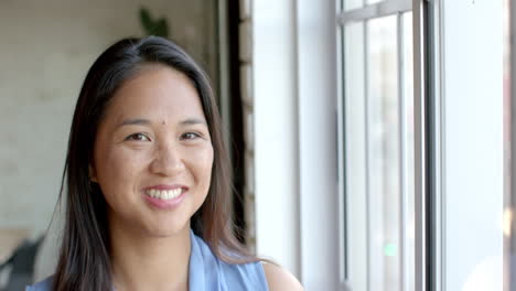 Biracial-woman-smiles-brightly-in-a-well-lit-business-room,-with-copy-space