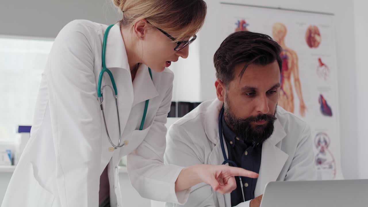 Ripresa a mano libera di due medici indaffarati che usano un computer portatile