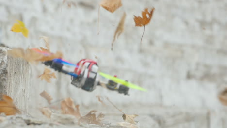el dron vuela rápido y bajo sobre el suelo levantando hojas del suelo en el viento