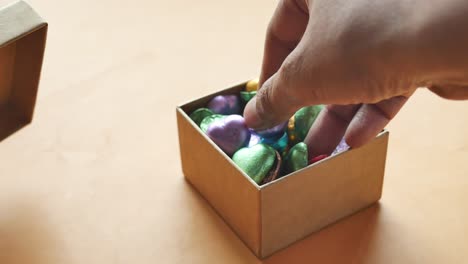 hand reaching into a box of colorful chocolates