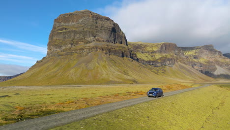 conducir un coche con la montaña lómagnúpur en el fondo en islandia - retroceso aéreo