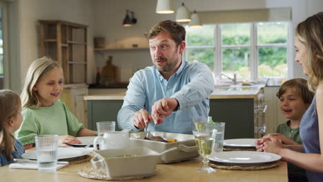 padre sirviendo comida como familia sentarse alrededor de la mesa en casa disfrutar de la comida juntos