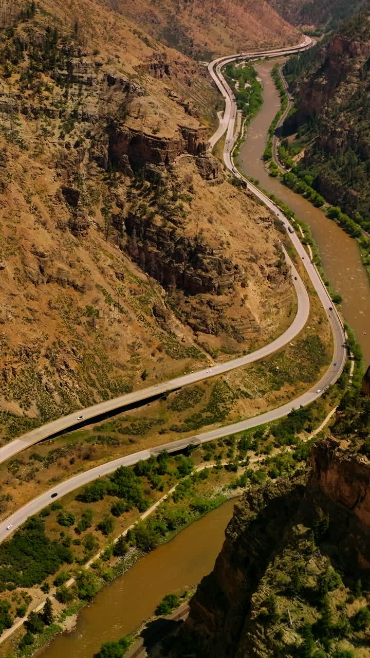Rocky hills of amazing mountains in Colorado, USA. River flowing at the foot of mountain and roads passing along the river from aerial view. Vertical video