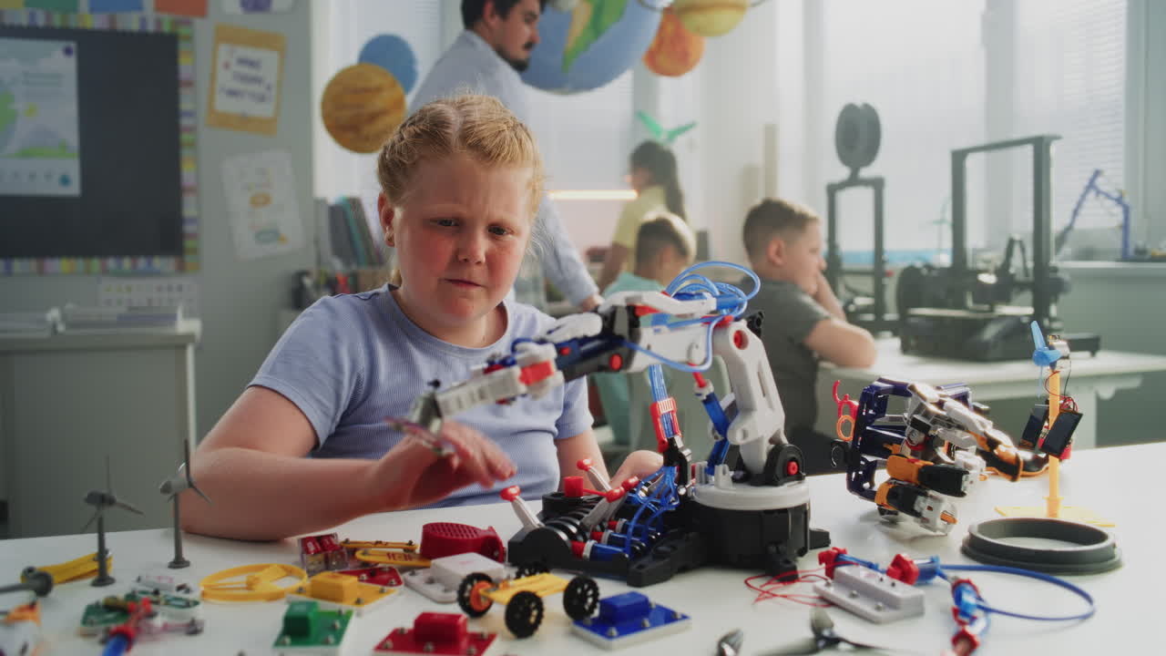 Elementary School Girl Examining Model of Innovative Robotic Arm Studying Engineering