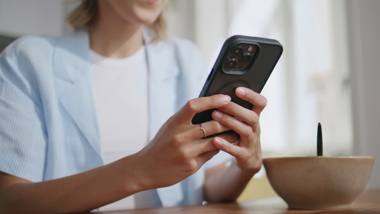 Girl hands texting mobile phone in morning home. Relaxed user holding cellphone