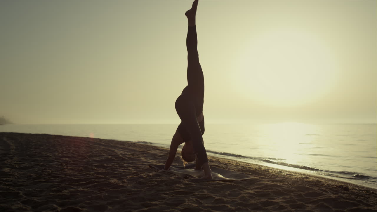 deportista practicando yoga de pie en la playa al amanecer. chica estirándose.