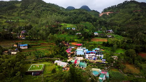 aerial dolly of traditional village with terraced farmlands in valley, dong van, vietnam at dusk, showcasing lush green hills and rural landscape