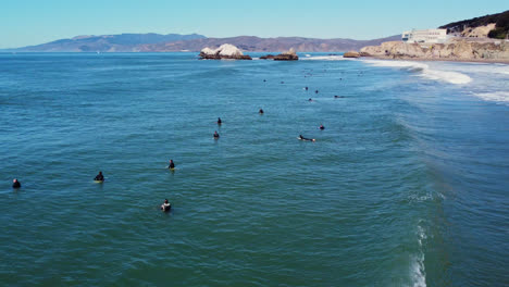 large group of surfers sitting and paddling out in the ocean waiting for a set of waves in san francisco, california