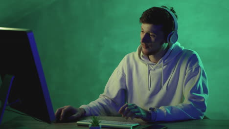 hombre trabajando con una computadora y auriculares inalámbricos en un fondo colorido