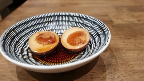 close-up-of-a-Japanese-onsen-egg-on-a-ceramic-plate-and-beautiful-wooden-table