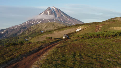 Drone-shot-following-a-truck-driving-on-a-gravel-road-onto-a-mountain