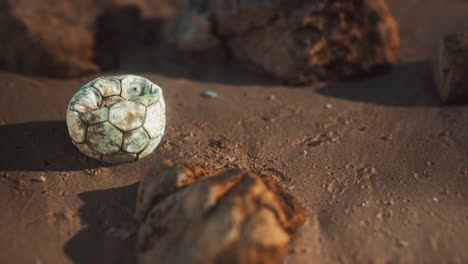 vieja pelota de fútbol en la playa de arena