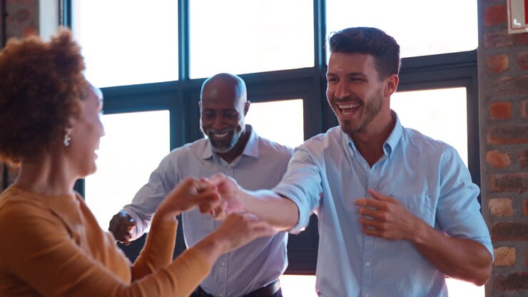 Business Team Celebrating In Meeting In Multi-Cultural Office With Colleagues Dancing And Having Fun