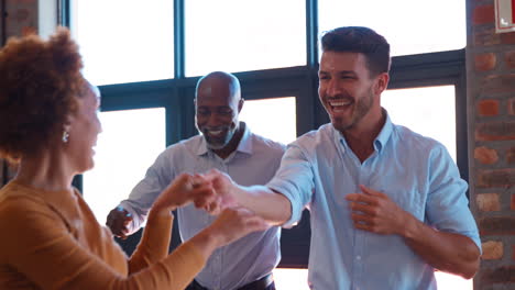 equipo de negocios celebrando en una reunión en una oficina multicultural con colegas bailando y divirtiéndose