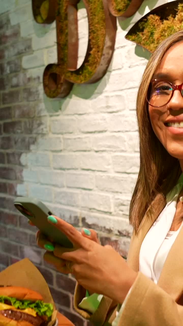 Woman using phone with burger nearby