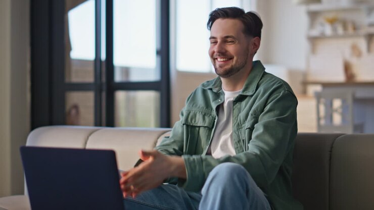 Happy hipster communicating laptop at couch closeup. Man talking video call
