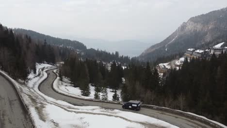 Ein-Wartungswagen-Mit-Werbung-Und-Leiter-Oben,-Der-Auf-Verschneiten,-Kurvenreichen-Straßen-In-Den-Bergen-Fährt