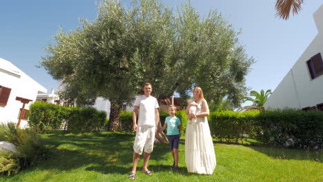 familia joven con dos hijos cerca del árbol de olivo en el jardín