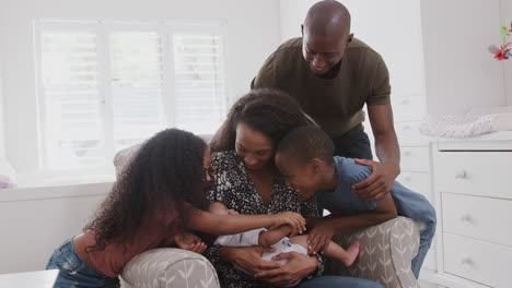 loving family in nursery at home cuddling baby son sitting in chair