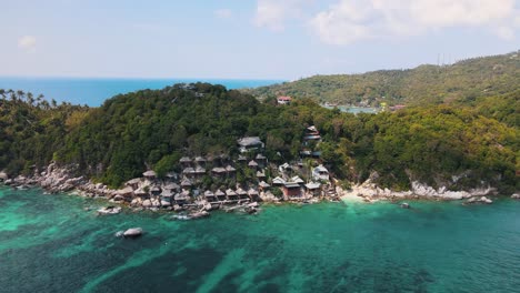 several houses of taatoh seaview resort built one above the other on a green rock at the beautiful green-blue shark bay in thailand