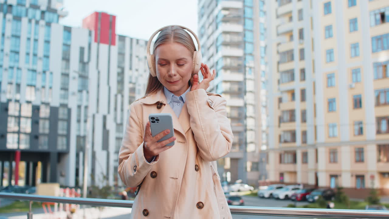 feliz mujer de negocios madura con auriculares inalámbricos bailando escuchando música en la calle del centro