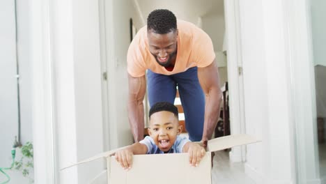 African-american-father-and-son-playing-with-a-cardboard-box-in-a-hallway
