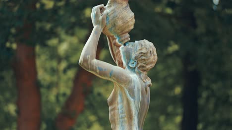 una estatua de una mujer bebiendo de la ánfora en el fondo borroso