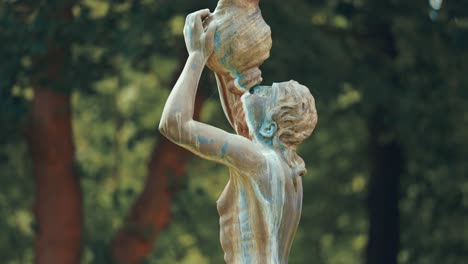 a statue of a woman drinking from the amphora on the blurry background