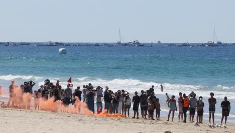 group of people watching orange smoke on beach