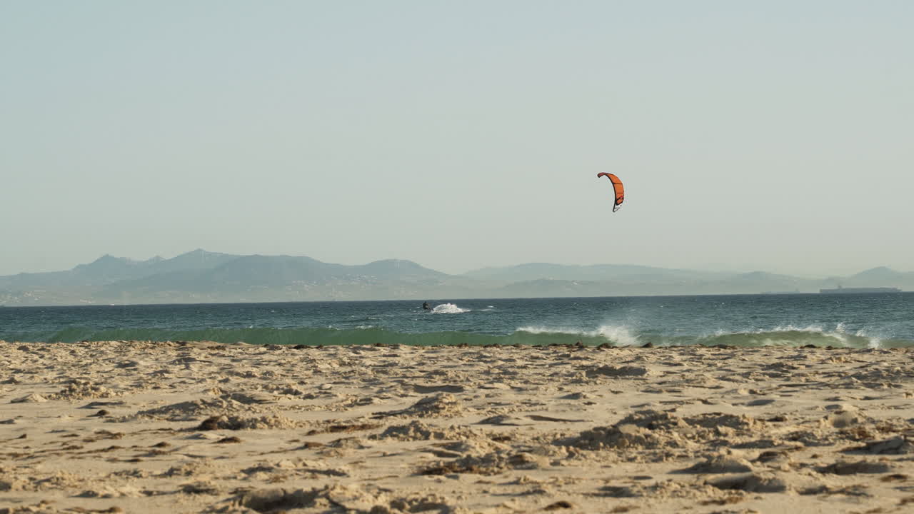 kiteboarder navegando en el mar por la playa de tarifa en españa con viento fuerte