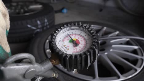 close up worker inflates summer tire and checks pressure with a air pressure indicator