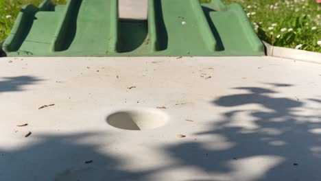 Putting-golf-ball-in-mini-golf-course-hole,-close-up-shot-on-a-swing