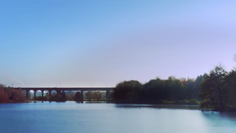 a time-lapse shot with a camera pan over the lake and a railway bridge