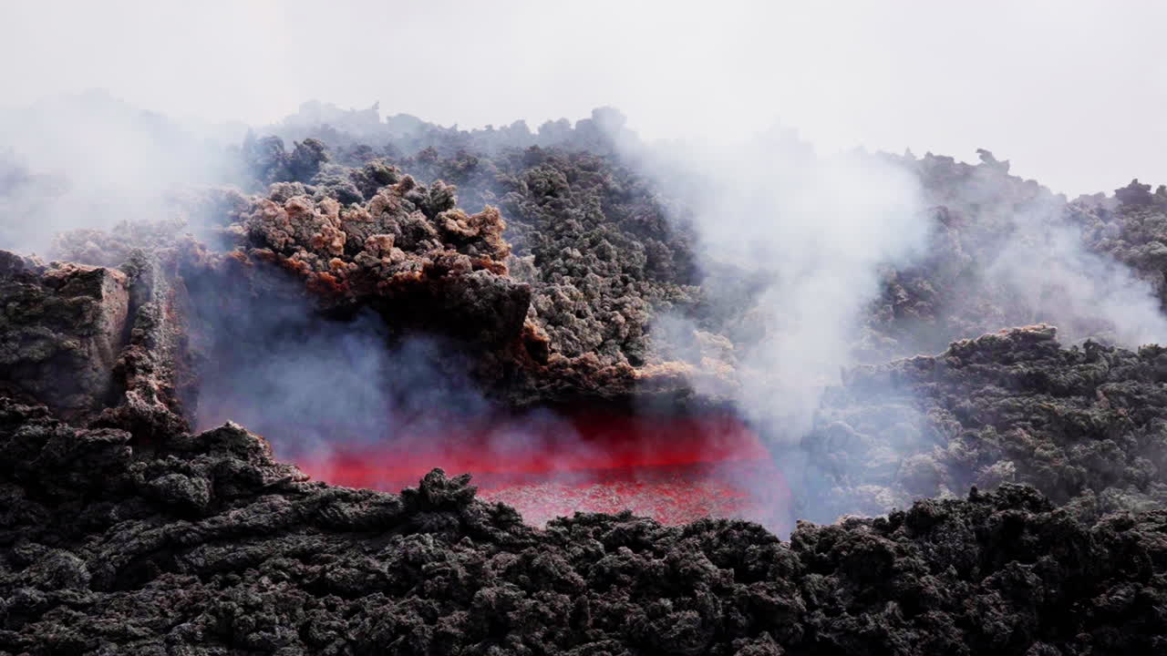 Fiery lava flows on smoky Mount Etna, evoking power and awe