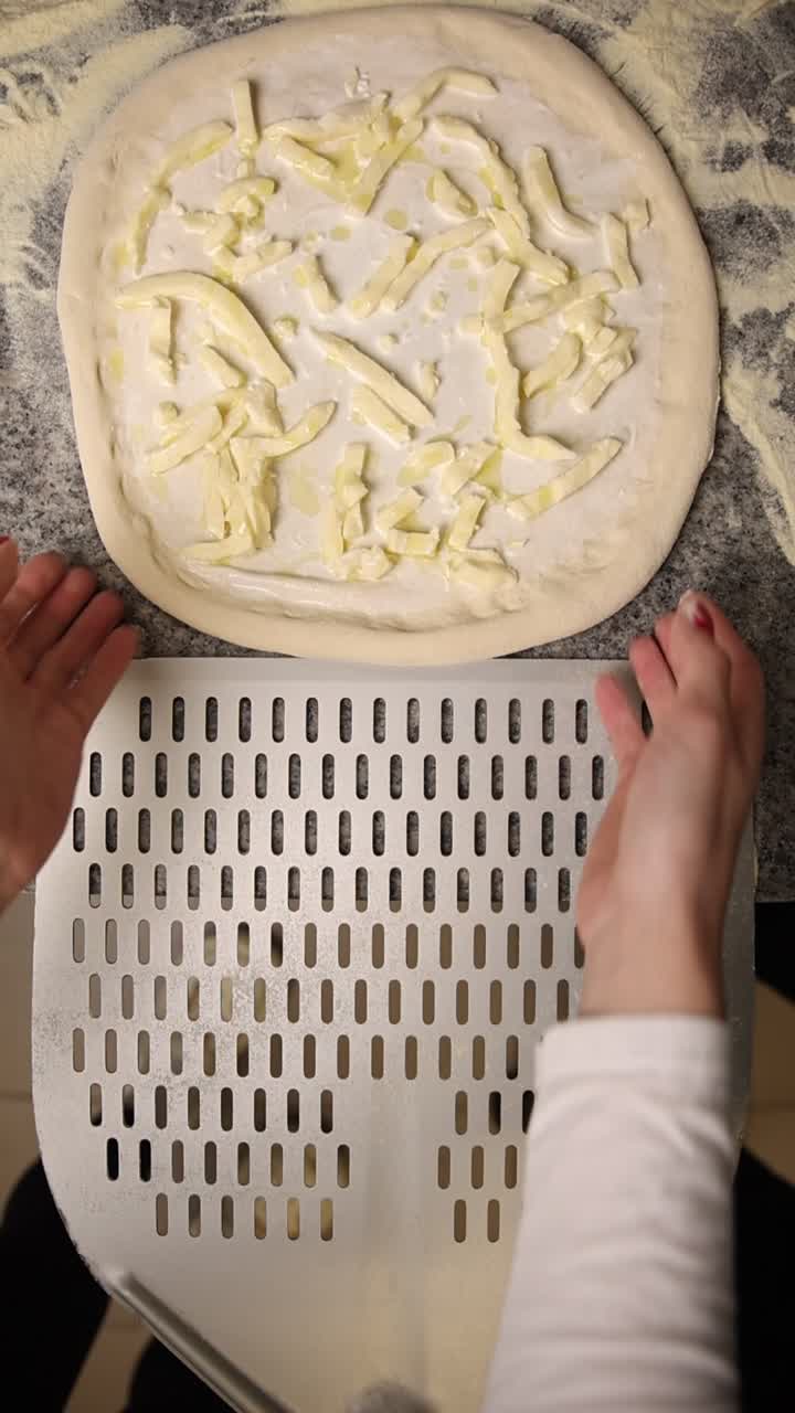 Mani che trasferiscono l'impasto della pizza con formaggio su una pala da pizza