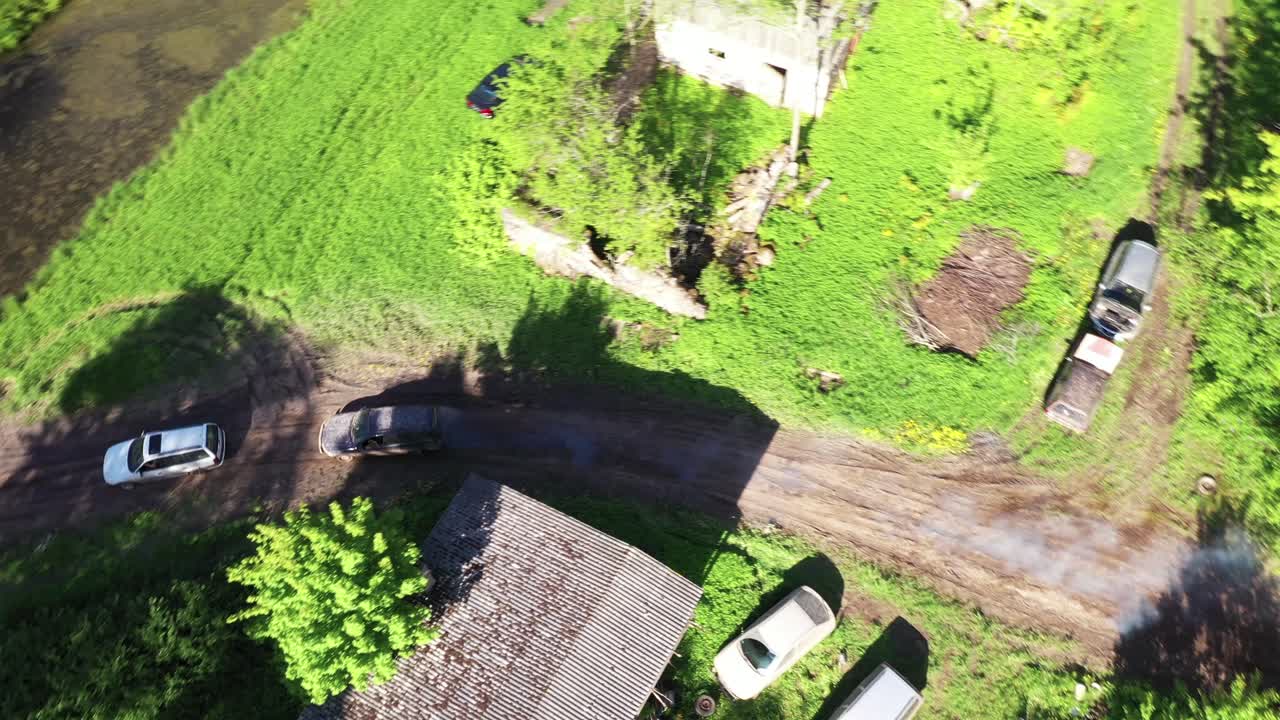 비포장 도로 트랙에서 경주하는 두 대의 자동차, 공중 후속 추적 샷, 화창한 날