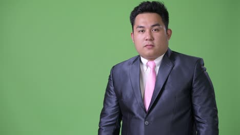 joven apuesto hombre de negocios asiático con sobrepeso contra un fondo verde