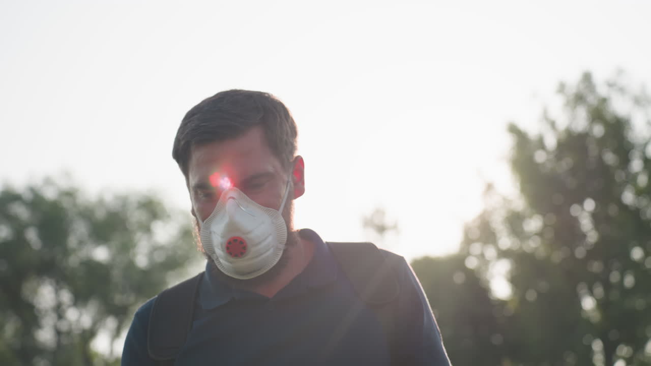 farmer wearing protective nose mask working in field with sunlight creating lens flare, close up of focused face against bright sky, environmental care and safety implied