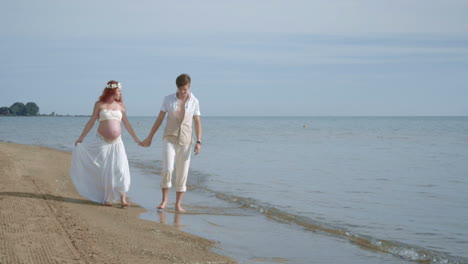 couple walking beach. pregnant couple on sea beach. pregnant woman on beach