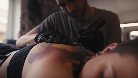 focus caucasian man tattooing woman at the studio.